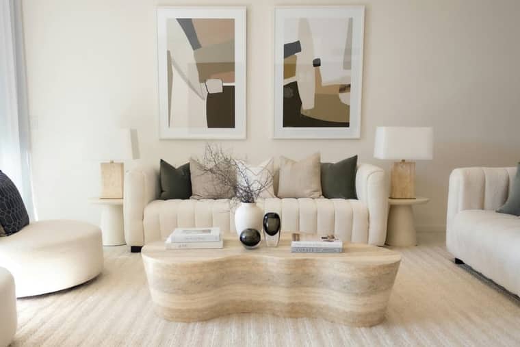 Residence 2: cream sofas, a bouclé ottoman and a sculpted travertine table.