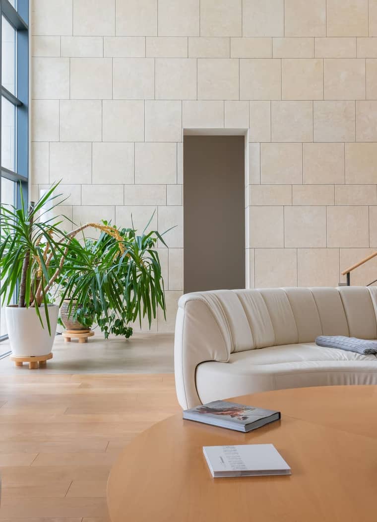 Residence 6: a sunlit room with a pale stone wall and a curved sofa.