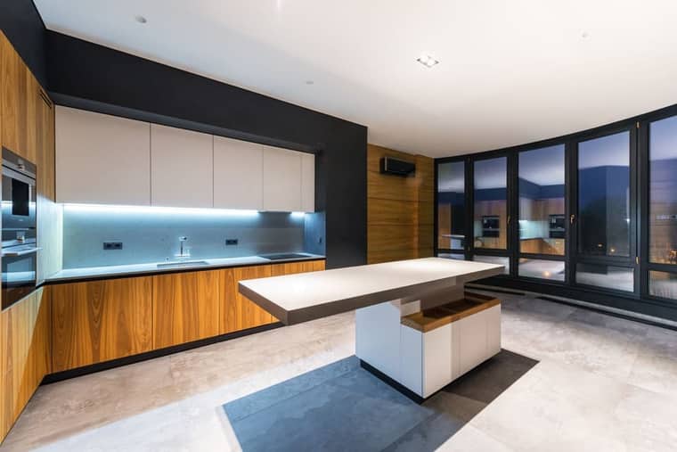 House 1: a kitchen in oak and white stone with big windows.
